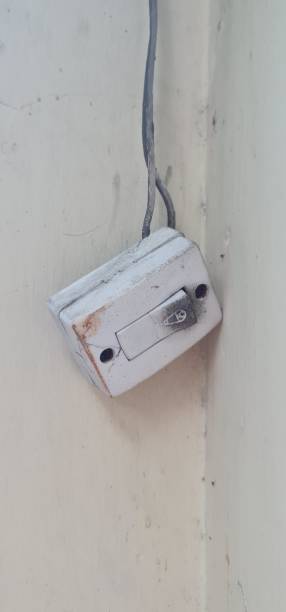 istock A broken house bell with its cables, dirty and shorted black, stuck to the light yellow wall. 2037112849