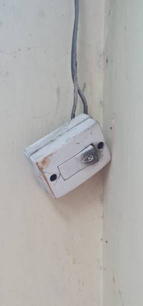 a broken house bell with its cables, dirty and shorted black, stuck to the light yellow wall. - shorted imagens e fotografias de stock