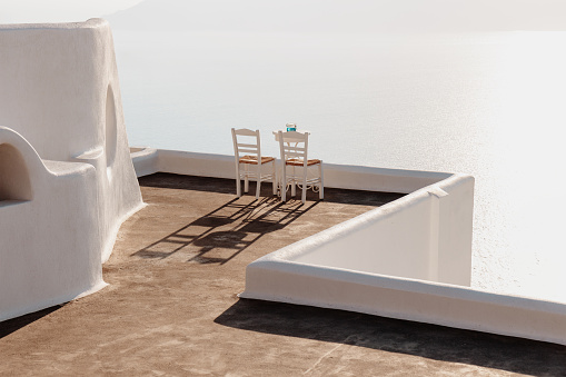 two white chairs on a balcony in Santorini, Firostefani and caldera view