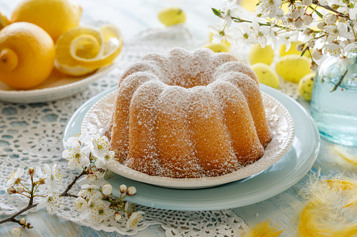 Easter lemon bundt cake, Babka sprinkled with powdered sugar on a festive table decorated with spring flowers, close up view