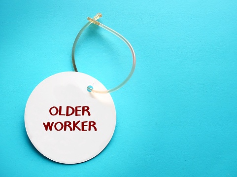Luggage ID tag on blue background with text written OLDER WORKER, trend of businesses hire more older people, senior employees work longer in rapidly aging society