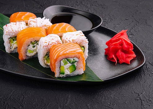 sushi rolls with salmon and crab on black plate