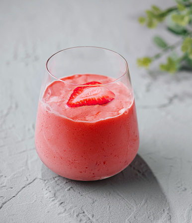 A glass of strawberry smoothie with strawberry slice