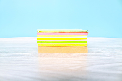 Stack empty sticky post note paper sheet on blue background. Stack of colorful sticky notes