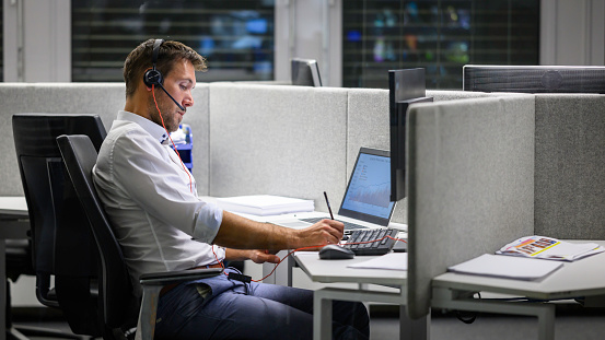 Businessman writing note in notepad with computer while working in office.