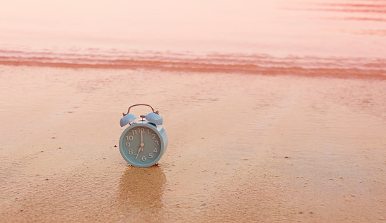 Concept alarm clock on beach in summer  island scene