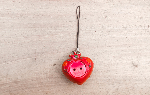 red love pendulum on a gray table. Blank space for writing. Aesthetic red love key chain