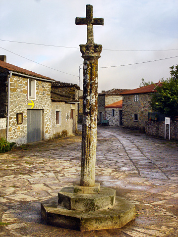 Ancient stone cross and town square seen along the camino de Santiago. A Coruña province, Galicia, Spain.