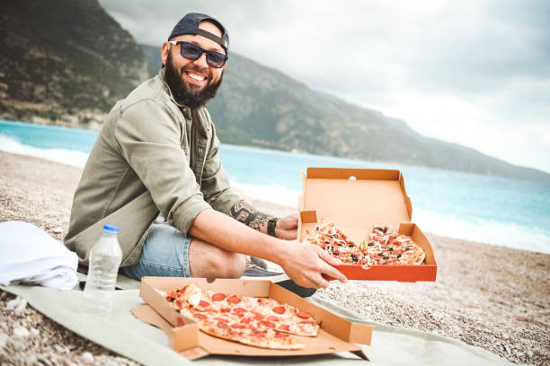 istock Man resting on the beach and eat pizza 2037278252