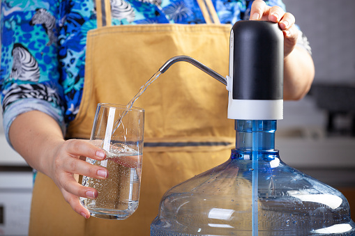 She pours a spring water into a water bottle.