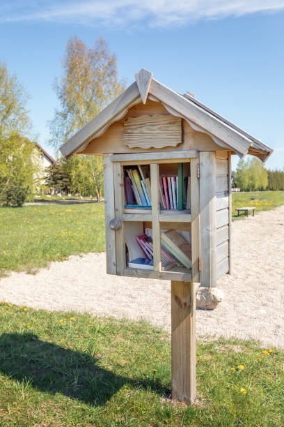 Small wooden, homemade house in the city park using for a library where citizens can take or leave books for free. Second life of the books..