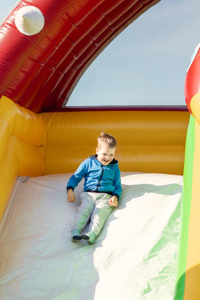 istock Little boy child rides on an inflatable multi-colored slide 2037338414