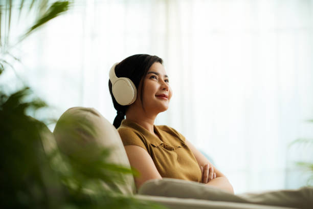 istock Woman Daydreaming with Music on Couch 2037363546