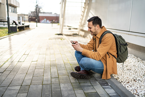 Handsome man using mobile phone while sitting outdoors
