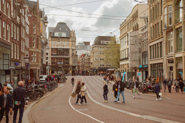 View from a street in Amsterdam crowded people walking through the narrow streets looking at the shops and shopping in the Netherlands