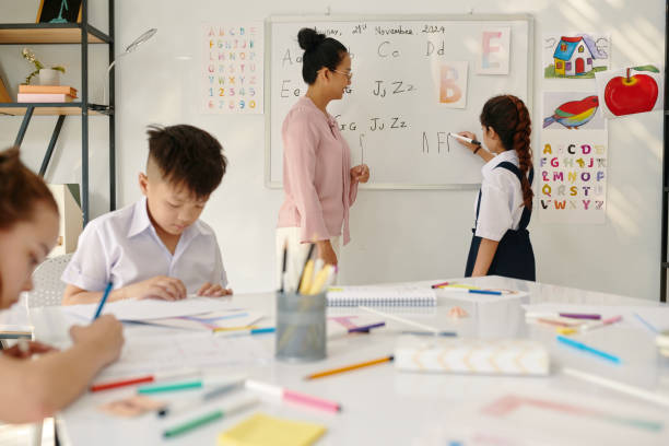 Schoolgirl Writing Letters on Whiteboard Schoolgirl writing on whiteboard letter that teacher asks her kids using smart board stock pictures, royalty-free photos & images