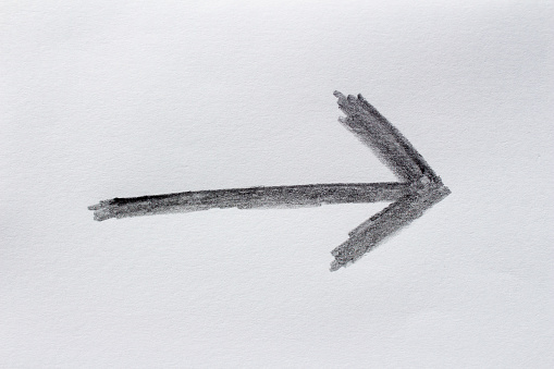 Charcoal hand drawn arrow symbol on white paper. Clipping path.
