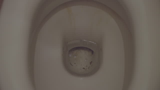 Flushing water in old dirty ceramic toilet bowl, close up view from above
