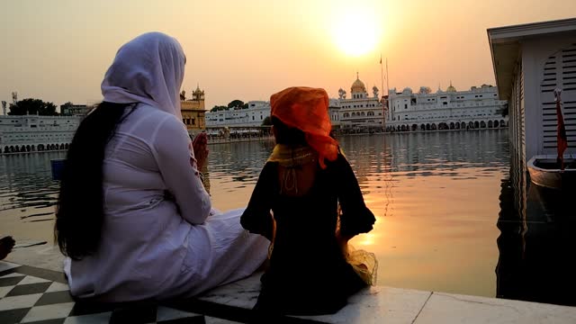 Family praying in golden temple during sunset time