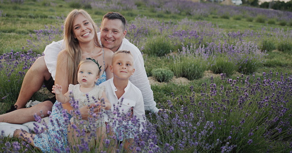 Portrait of a happy family with two children sitting on a blooming lavender field.