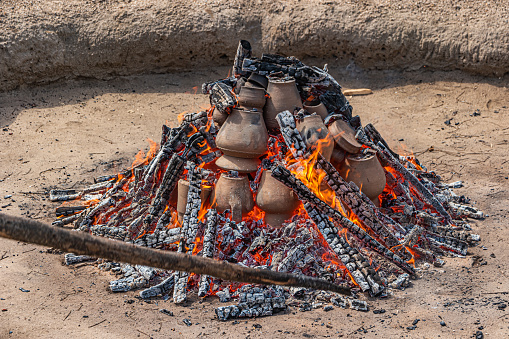AMARANTE, PORTUGAL - CIRCA APRIL 2022: Stage of covering with soil of the bonfire with the pieces of clay piled up during the cooking process of the black clay of Gondar on circa april, 2022 in Amarante, Portugal.