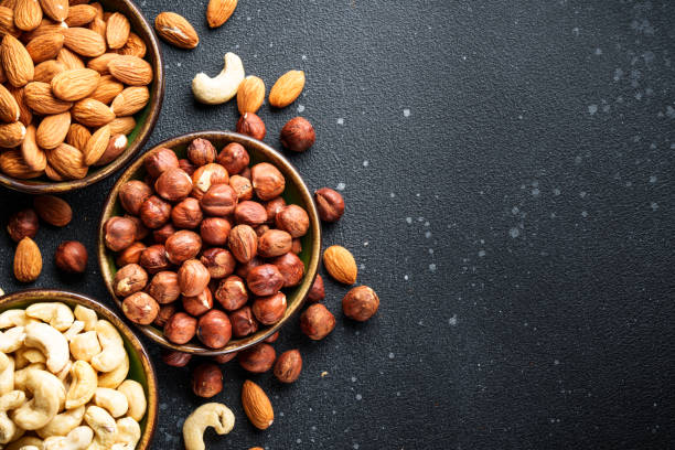 istock Nuts assortment in bowls at black background. 2037551195
