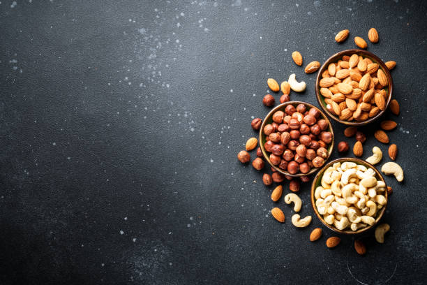 istock Nuts assortment in bowls at black background. 2037551198