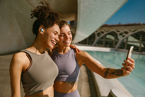 Portrait of two sporty smiling young woman after running making selfie outdoors