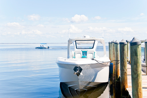 Jetty with Recreational boats at the Caloosahatchee River in Florida, USA. One boat moored at the jetty another boat on the river on the horizon.