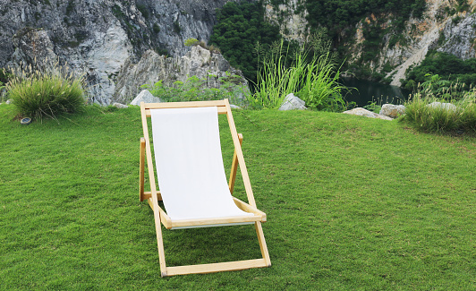 Empy white plastic garden chair standing on a green lawn in front of a cornfield in evening light. Seen in Bavaria, Germany in August.