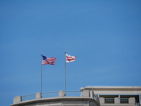 large flag of the united states and District of Columbia fluttering into the wind on a blue sky day