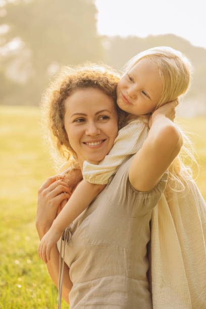 Happy mother holding her child in her outstretched hands, throwing up and playing on the nature. People. Lifestyle, Family relationships