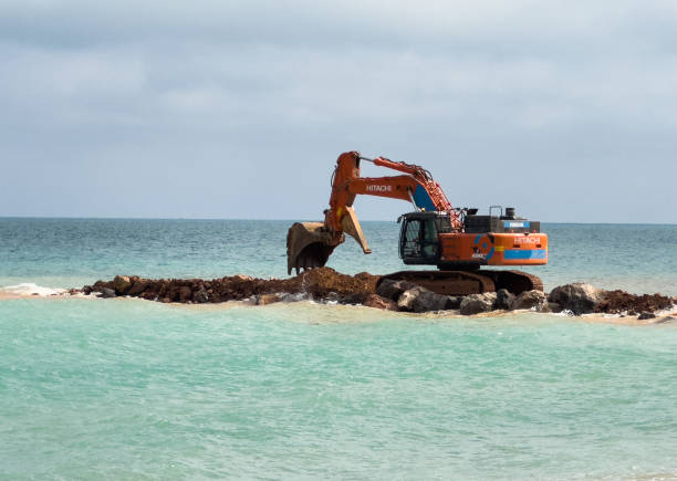 Breakwater construction at coastal. Beach regeneration on sea coastline. Excavator laying stones and Rubble during breakwater construction. Beach renovation. Shore protection. April 23, Nules, Spain.