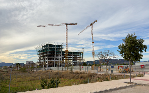 Construction site by developer Quevedo and Vasco Group. Crane on formwork. Hotel apartments, Housing renovation. Urbanizable land in Port de Sagunt, Spain, province of Valencia. 12, April, 2023.