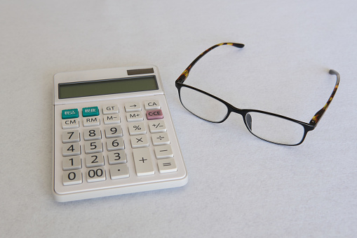 [Life planning] Calculator and glasses on a white background.