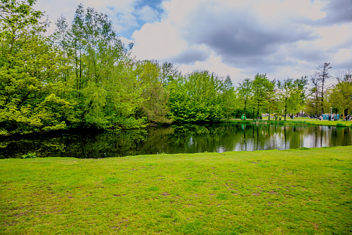 Turin, Piedmont, Italy  - May 2, 2021: View of a public park with people around a pond, spring.