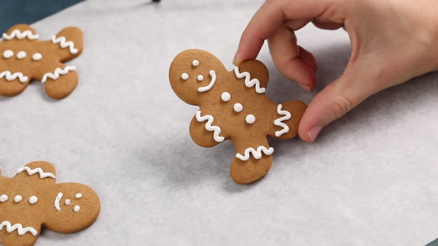 Decorating gingerbread man Christmas cookie, pastry chef decorating with icing