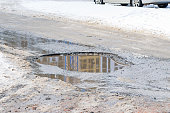 pothole on an asphalt road with a puddle during the spring or winter thaw. poor quality road surface