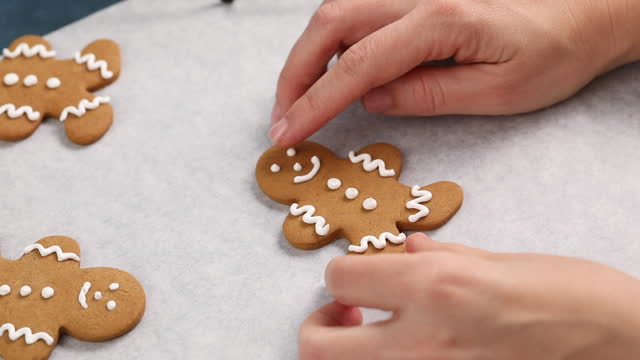 Decorating gingerbread man Christmas cookie, pastry chef decorating with icing