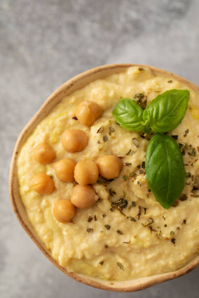 A comforting dish of hummus made with chickpeas and served with crackers, a staple food in many cuisines, placed on a metal tableware