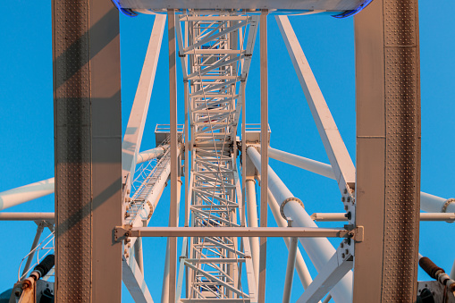 A bottom view of the Ferris wheel structure against a blue sky background. metal structures Ferris wheel elements