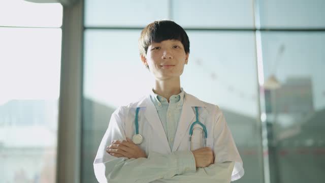 Portrait of an Asian doctor standing with his arm crossed at the doctor's office