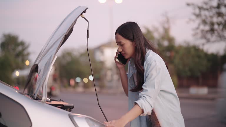 A woman is experiencing a car breakdown and calling for help on the roadside