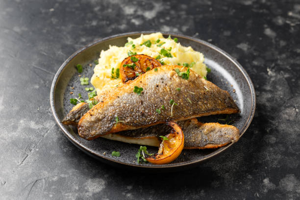 Pan fried sea bass fillets served with mashed potatoes and caramelised lemon