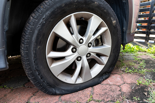 Deflated flat car tire with rupture at the side of the wheel