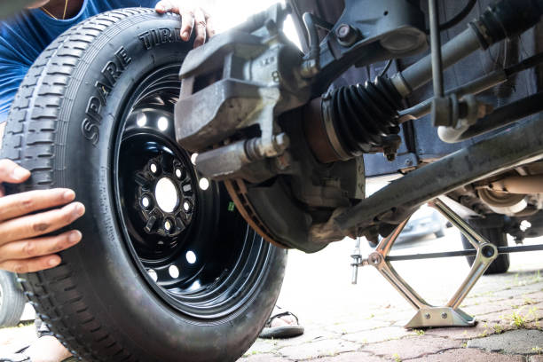 istock Person attempting to fix or replace temporary spare tire onto vehible after omiting punctured flat tire 2037845521