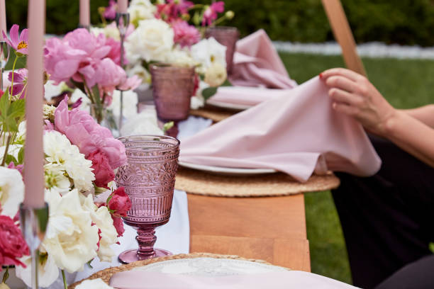 istock Picnic aesthetics table setting, flowers arrangement. Hands arranging flowers on a festively decorated table. Hospitality and event organization concepts 2037931569