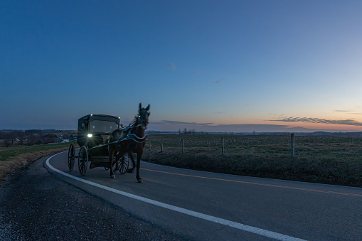 A horse-drawn Amish buggy at sunset on a country road near Charm, Ohio.