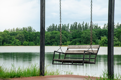 Beautiful landscapes of lake and forest there is a lonely swing by the lake and light hitting the water surface on sky cloudy with soft sunlight background.