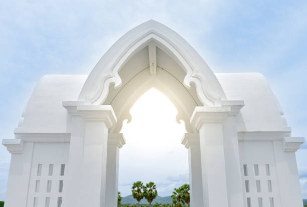 Beautiful white entrance arch architecture with Thai temple pattern with Indian pattern or a white Thai temple chapel with sunlight in the center on sky and forest background.